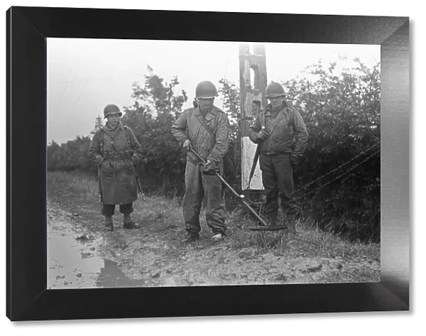 US Soldiers searching for land mines on the grass verges of the roads in