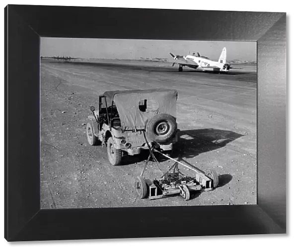 R. A. F. engineers search an airfield for mines using a magnetic sweep attached to a jeep