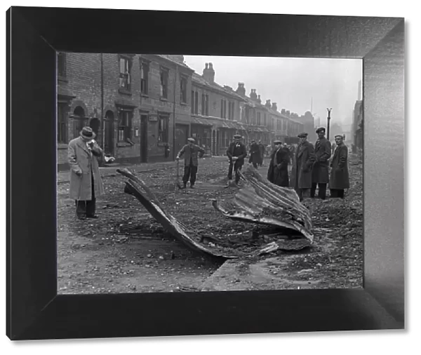 Workmen inspect the remains of a Anderson shelter that was blown over the rooftops into