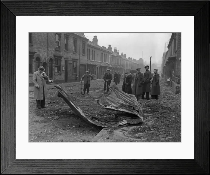 Framed Print : Workmen inspect the remains of a Anderson shelter that was blown over the rooftops into Framed Print : Workmen inspect the remains of a Anderson shelter that was blown over the rooftops into