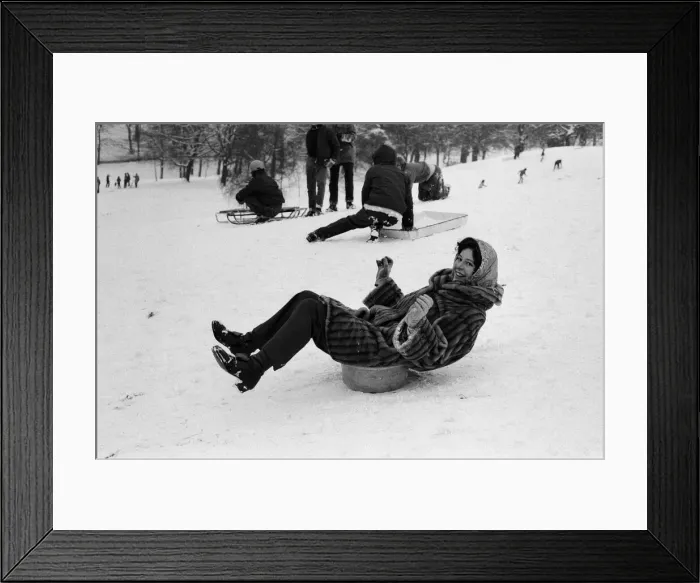 Framed Print : A woman sledging on a washing up bowl in Greenwich Park, London, 27th December 1970 Framed Print : A woman sledging on a washing up bowl in Greenwich Park, London, 27th December 1970