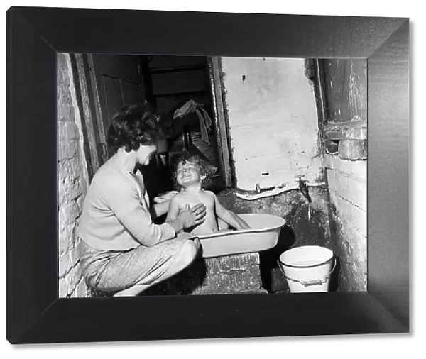 Slum housing, Ellison Street, Liverpool. Two-year-old Jean Ann Jameson takes a bath