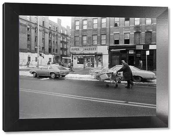 A man pushing a shopping trolley in the road in New York. 13th February 1981