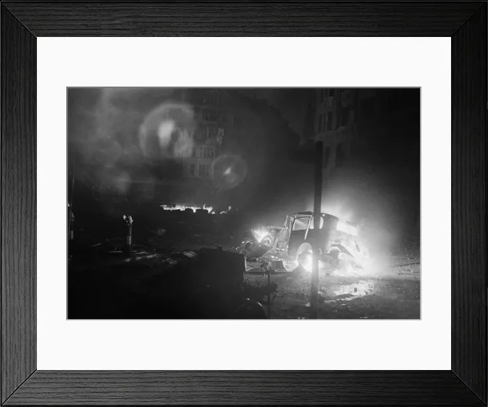 Framed Print : The wreckage of a car a blaze after being hit by a bomb