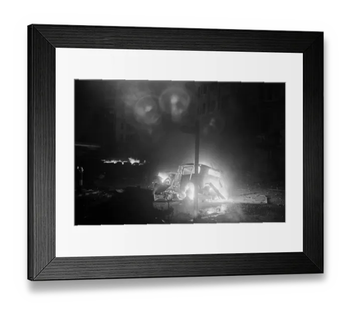 Framed Print : The wreckage of a car a blaze after being hit by a bomb
