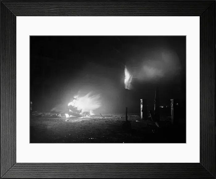 Framed Print : The wreckage of a car a blaze after being hit by a bomb