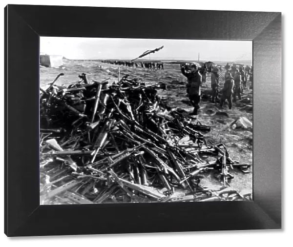 ARGENTINE SOLDIERS THROWING THEIR WEAPONS ONTO A PILE AT PORT STANLEY AFTER SURRENDERING