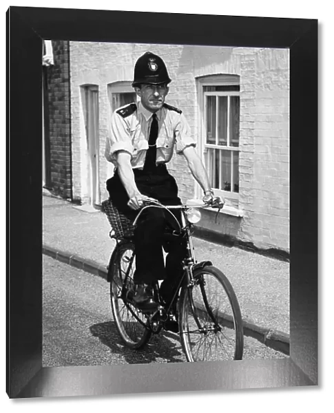 A police officer doing his rounds on a bicycle in Cambridgeshire. July 1964