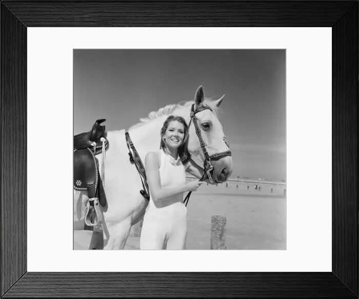 Framed Print : Diana Rigg, who plays Emma Peel, smiling with a white horse on the beach at St Mary Framed Print : Diana Rigg, who plays Emma Peel, smiling with a white horse on the beach at St Mary