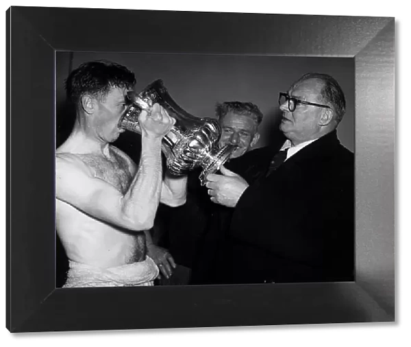 Arsenal skipper Joe Mercer celebrates his teams FA Cup win by drinking champagne