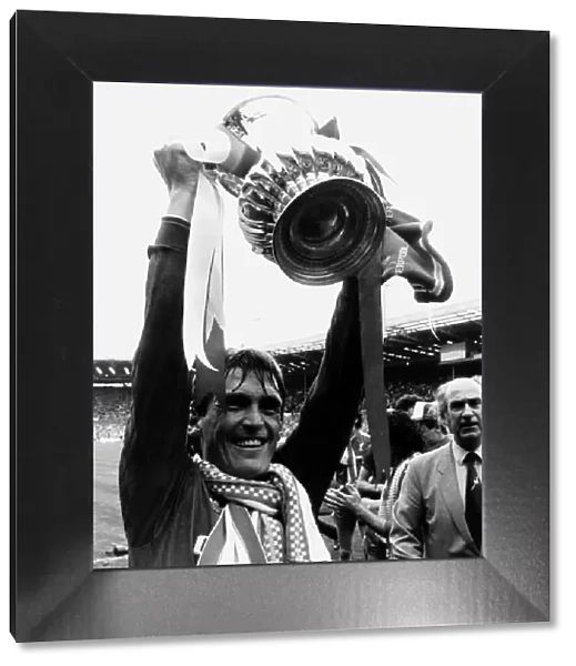 Liverpool player manager Kenny Dalglish holding the trophy aloft after their win against