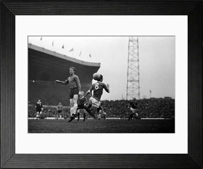 Framed Print : Brian Kidd of Manchester United in an aerial challenge for the ball with an Ipswich Town