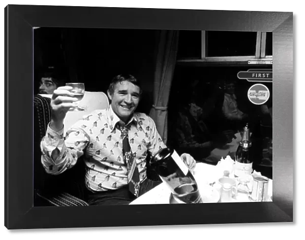 Football manager Malcolm Allison drinking champagne n the train