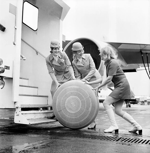 3 air hostesses rolling along a wheel of some sort A 2 Local Caption