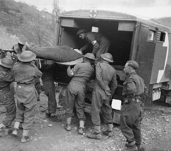 A 8th Army casualty being loaded into a motor ambulance
