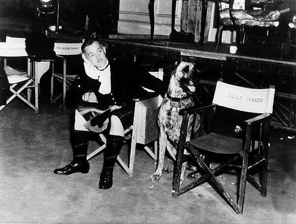 Actor Alec Guinness patting a doberman dog on set of film To Paris with Love