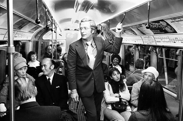 Actor Michael Caine travelling on the underground train at Aldwych tube station during