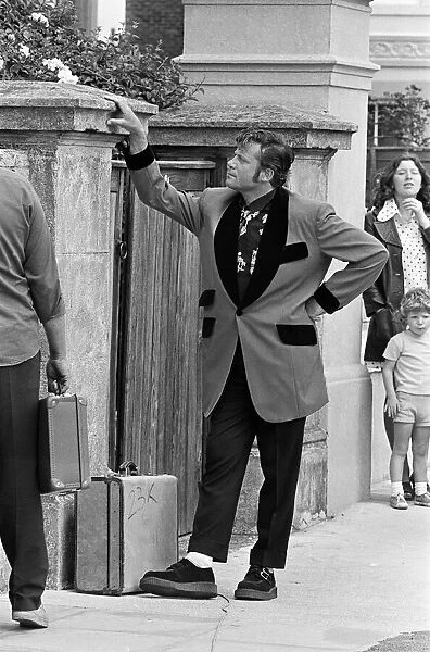 Actor Oliver Reed dressed in Teddy Boy clothing during a break in filming of the pop