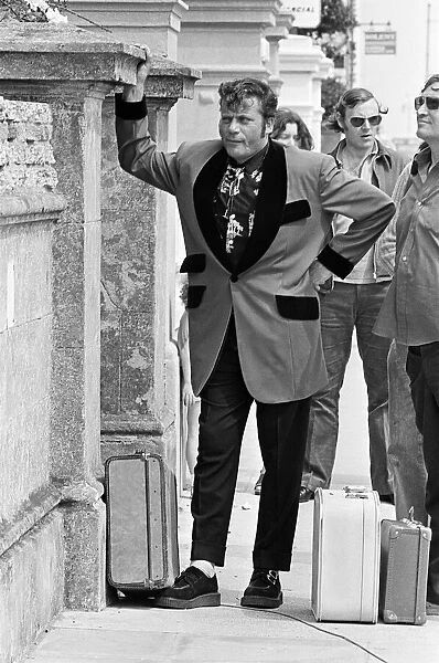Actor Oliver Reed dressed in Teddy Boy clothing during a break in filming of the pop