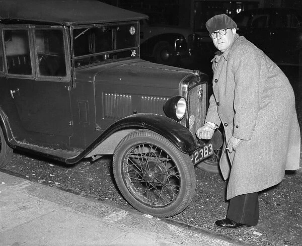 Actor Peter Sellers seen here trying to start his Austin 7 motor car outside the Paris