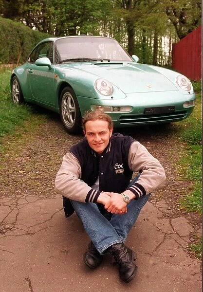 Actor Simon Weir poses by the Porsche Targa 911 car May 1997 sitting on ground