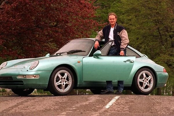 Actor Simon Weir poses by the Porsche Targa 911 car May 1997 standing with door open