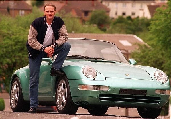 Actor Simon Weir poses by the Porsche Targa 911 car May 1997 with foot resting on tyre