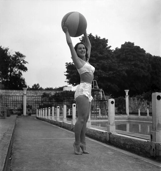Actress Deidre De Peyer holding up a ball at Roehampton swimming pool