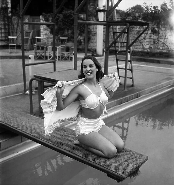 Actress Deidre De Peyer poses sitting on the diving board at Roehampton swimming pool