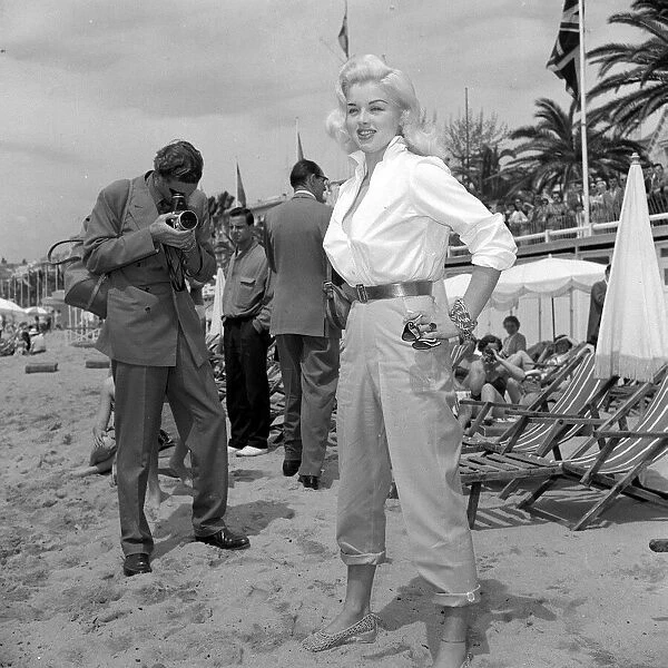 Actress Diana Dors has her picture taken by a photographer on the beach at cannes Film
