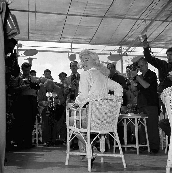 Actress Diana Dors surround by photographers and press men at the Cannes film Festival
