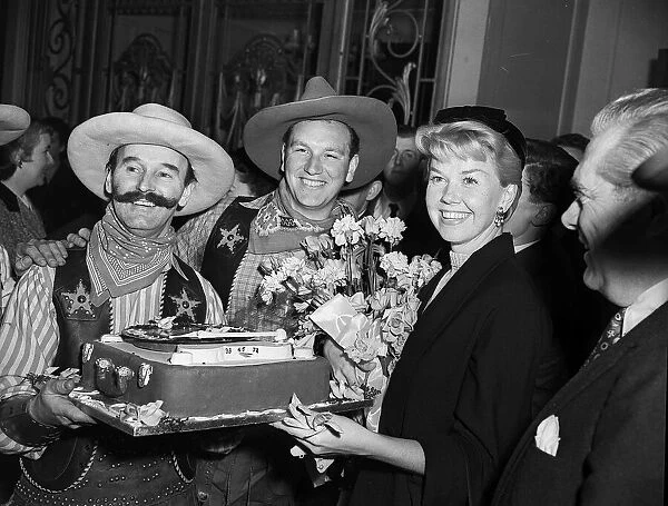 Actress Doris Day is presented with a cake by a couple of cowboys April 1955
