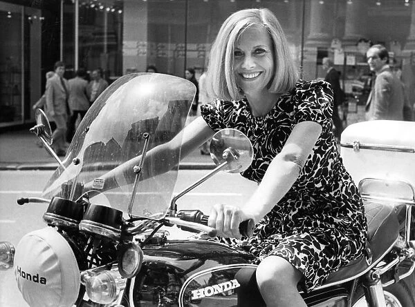 Actress Honor Blackman posing on a motorbike