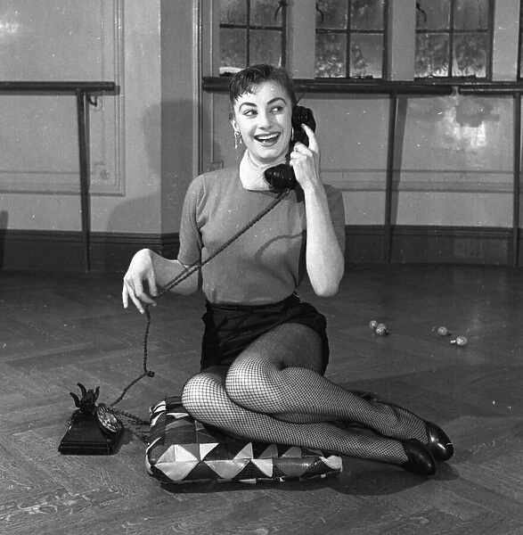 Actress Jean Marsh aged 17 posing sitting ona cushion and holding a phone