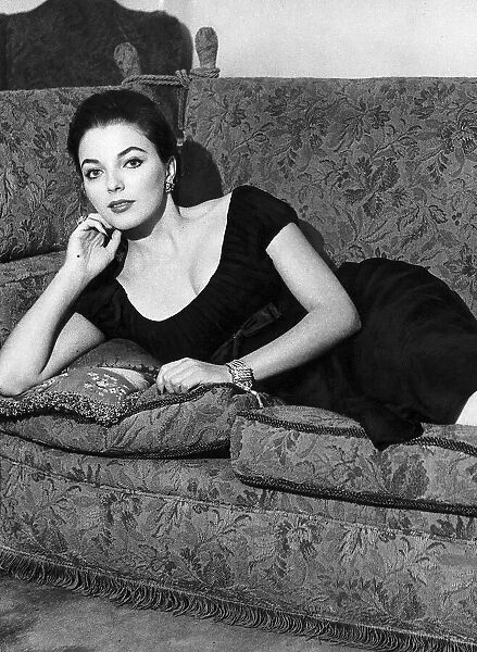 Actress Joan Collins poses on her sofa June 1956