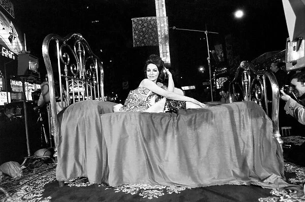 Actress Julie Newmar lying on a brass bed in New York