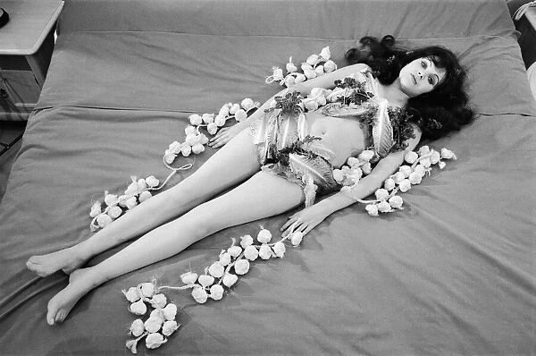 Actress MAdeline Smith lying on a bed covered with garlic and lettuce