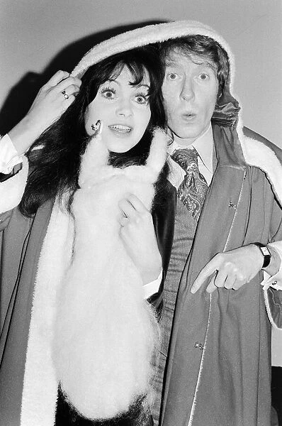 Actress Madeline Smith poses with Michael Crawford dressed in Father Christmas attire at