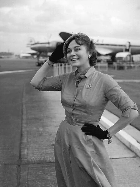Actress Marta Torren holds on to her hat at the airport September 1956