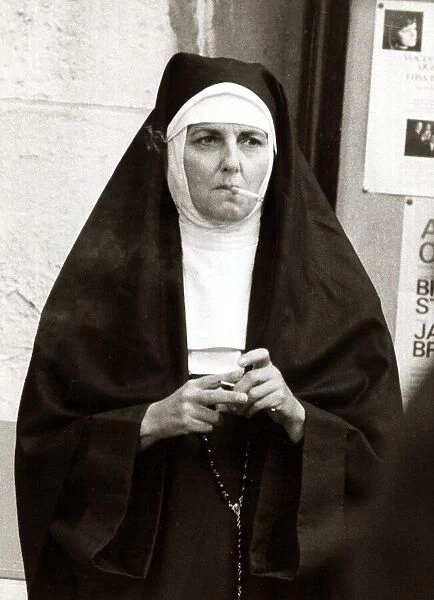 Actress playing the part of a nun takes a cigarette break during filming for A Man Called