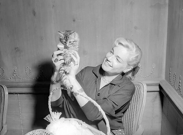 Actress Simone Signoret holding a tiny kitten at a press conference