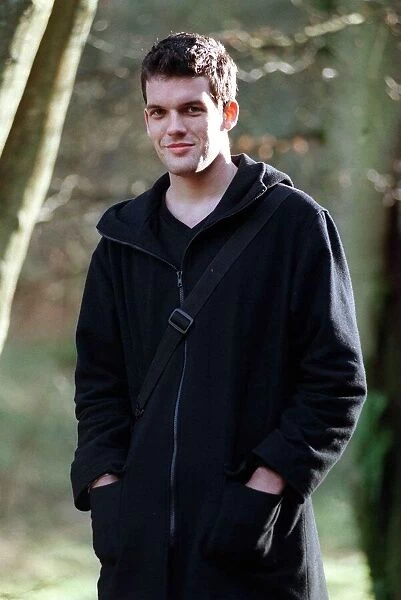 Adam Sinclair actor January 1999 in park, wearing a black coat, hands in pockets