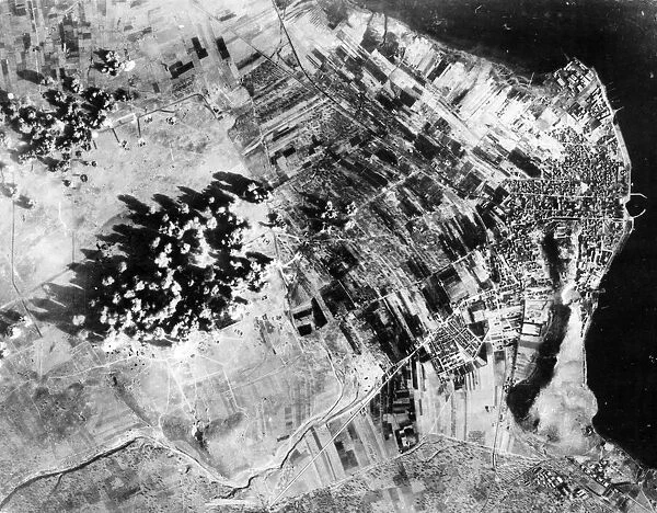 Administration buildings, hangers and revetments are covered by bomb bursts during a