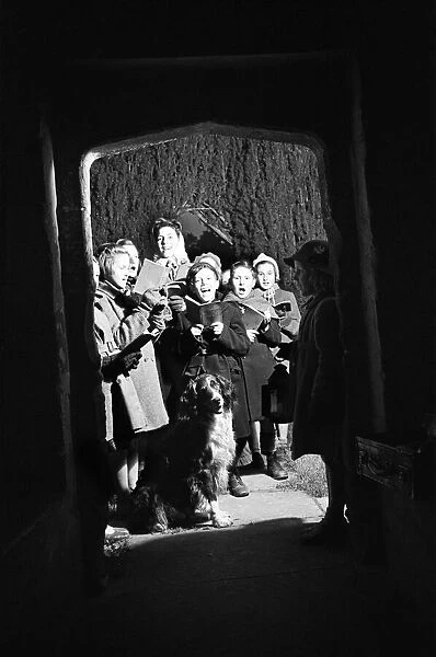 Adults and children carol singing at night time outside Sulgrave Manor, Northamptonshire