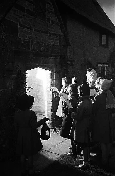 Adults and children carol singing at night time outside Sulgrave Manor, Northamptonshire
