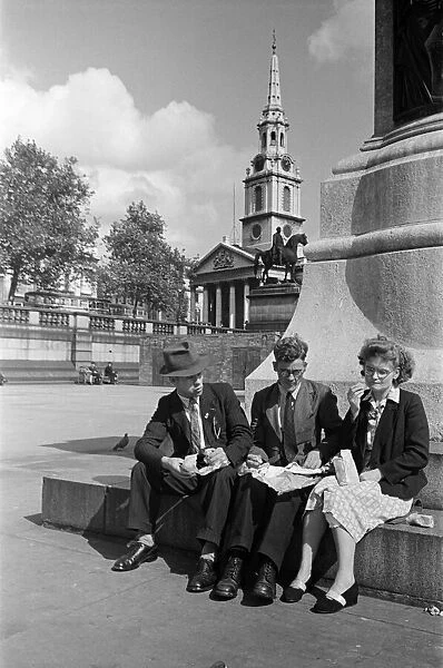 Three adults eating their packed lunch in Trafalgar Square, Westminster, London
