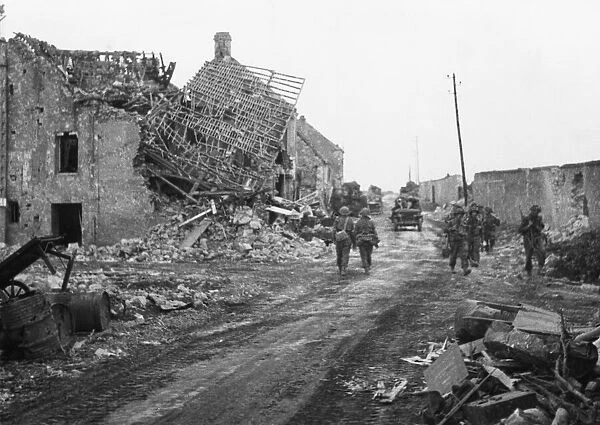 The advance towards Caen. Infantry making their way through the ruined village of Lebisey