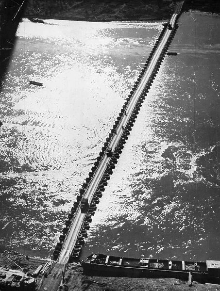 Aerial view of the 1st US Army Trucks and equipment rolling across a pontoon bridge over