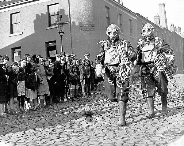 Two air raid wardens cause a stir as they stroll in February 1939 in full regalia