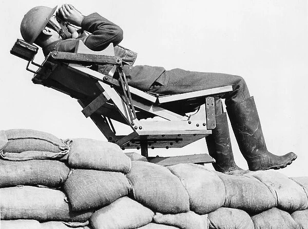 An aircraft observer lies back in a chair on top of a sand bag enforcement scanning